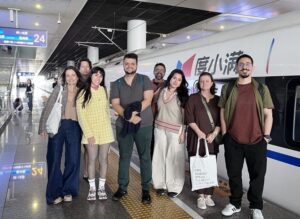 Brazilian school group posing with a high-speed train at the station